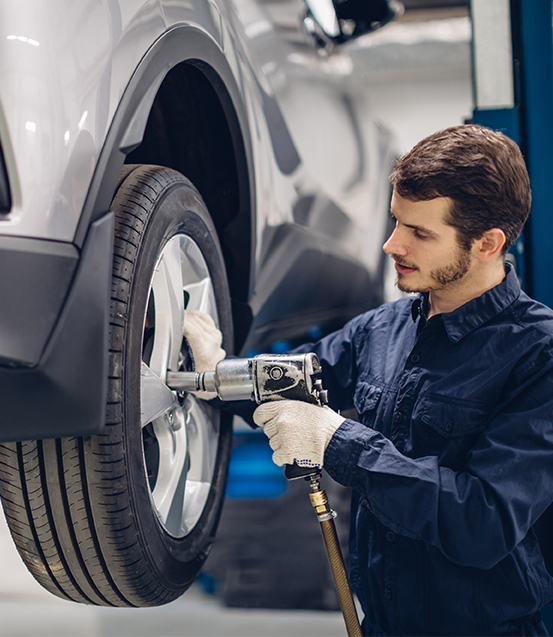 ein Mitarbeiter in Arbeitskleidung die Radschrauben anzieht