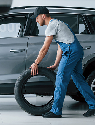 Ein Mitarbeiter in Arbeitskleidung rollt ein großes Autorad